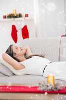 Composite image of relaxed brunette lying on the couch at christmas