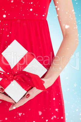 Composite image of woman in red dress holding gift