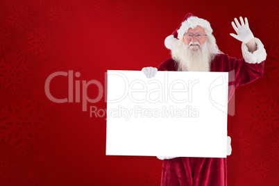 Composite image of santa holds a sign and is waving