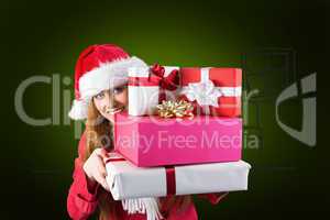 Composite image of festive redhead holding pile of gifts