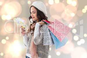 Composite image of happy brunette holding cash and shopping bags