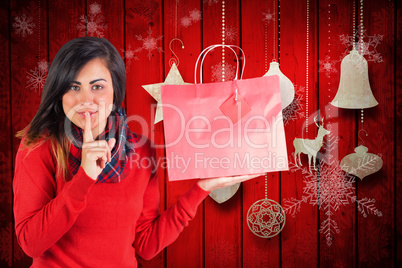 Composite image of brunette holding gift bag and keeping a secre