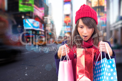Composite image of shocked brunette opening gift bag
