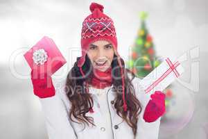 Composite image of festive brunette in winter clothes holding gi