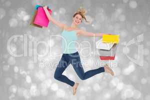 Composite image of excited blonde jumping while holding shopping