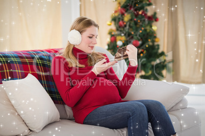 Composite image of pregnant woman looking at baby shoes sitting
