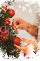 Composite image of woman hanging christmas decorations on tree