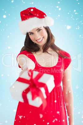 Composite image of festive brunette holding gift