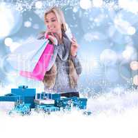 Composite image of blonde in winter clothes holding shopping bag