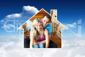Composite image of house frame in couple sitting on floor