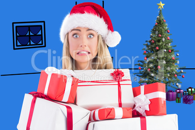 Composite image of festive blonde holding pile of gifts