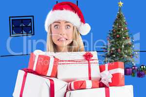 Composite image of festive blonde holding pile of gifts