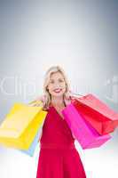 Stylish blonde in red dress holding shopping bags
