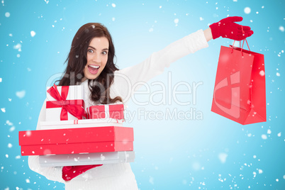 Composite image of excited brunette holding gifts and showing sh