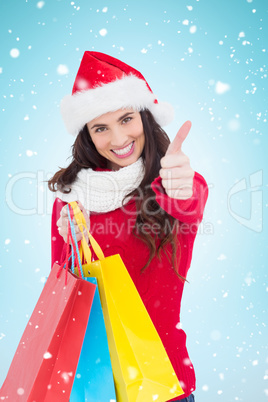 Composite image of festive brunette holding gifts and thumb up