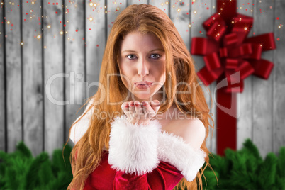 Composite image of festive redhead blowing a kiss