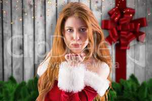Composite image of festive redhead blowing a kiss