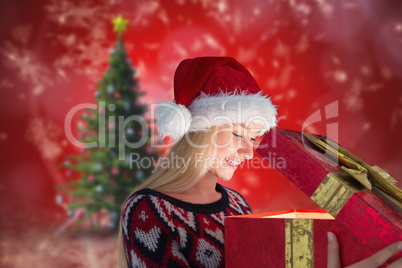 Composite image of festive blonde opening a gift