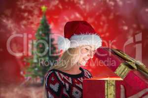 Composite image of festive blonde opening a gift