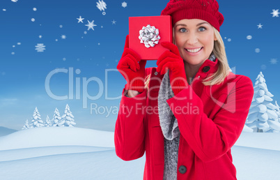 Composite image of festive blonde holding red gift