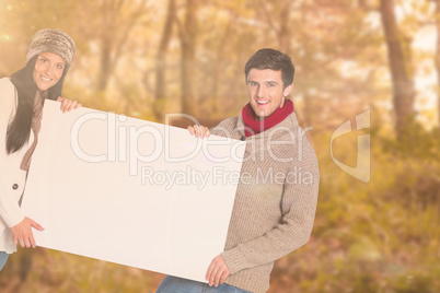 Composite image of young couple holding a poster