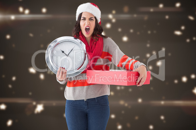 Composite image of surprised brunette holding a clock and gift