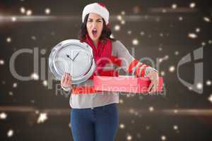 Composite image of surprised brunette holding a clock and gift