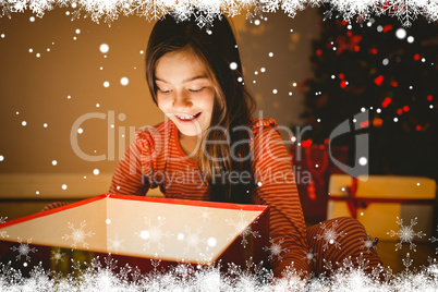 Composite image of little girl opening a glowing christmas gift