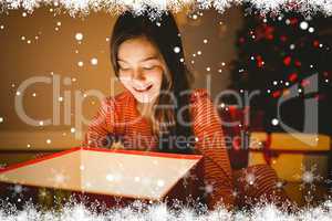 Composite image of little girl opening a glowing christmas gift