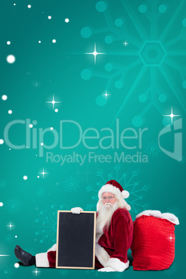 Composite image of santa sits leaned on his bag with a board