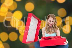 Composite image of pretty woman opening a gift smiling at it
