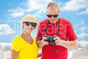 Composite image of happy mature couple wearing sunglasses