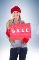 Blonde in winter clothes holding sale sign