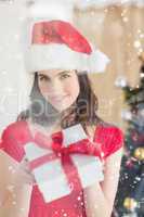 Composite image of beauty brunette showing gift at christmas