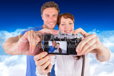 Composite image of couple using camera for picture