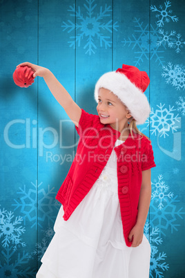 Composite image of cute little girl wearing santa hat holding ba