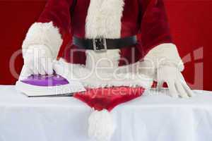 Composite image of father christmas is ironing his hat