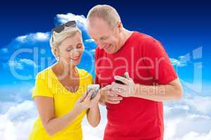 Composite image of happy mature couple looking at smartphone tog