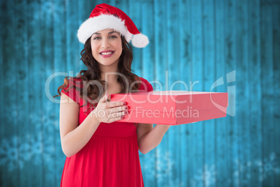 Composite image of festive brunette holding red box