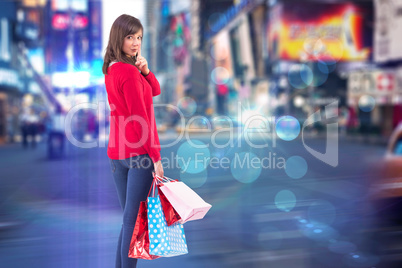 Composite image of festive brunette holding gift bags