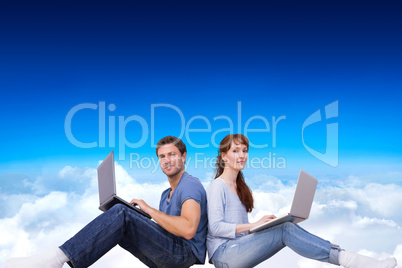 Composite image of couple both using laptops separately