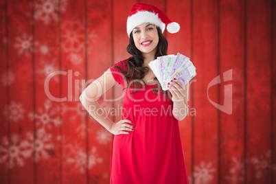 Composite image of festive brunette presenting her cash Composite image of festive brunette presenting her cash