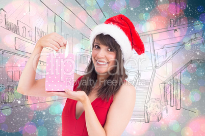 Composite image of festive brunette holding a gift bag