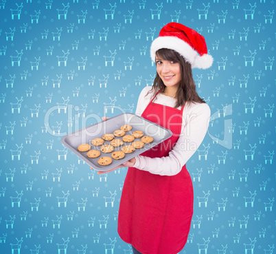 Composite image of brunette in santa hat offering hot cookies