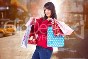 Composite image of happy brunette holding shopping bags
