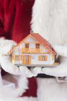 Composite image of santa holds a tiny house in his hands