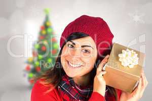 Composite image of pretty brunette in hat holding a gift