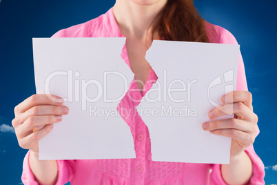 Composite image of woman holding torn sheet of paper