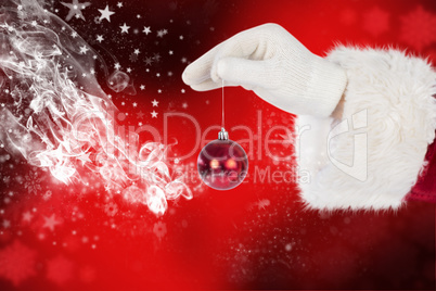 Composite image of santas hand is holding a christmas bulb