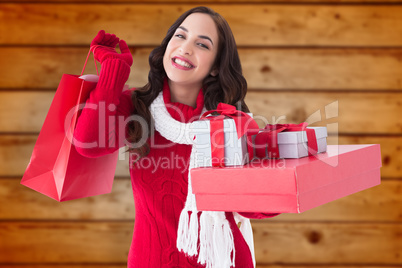 Composite image of smiling brunette holding christmas gifts